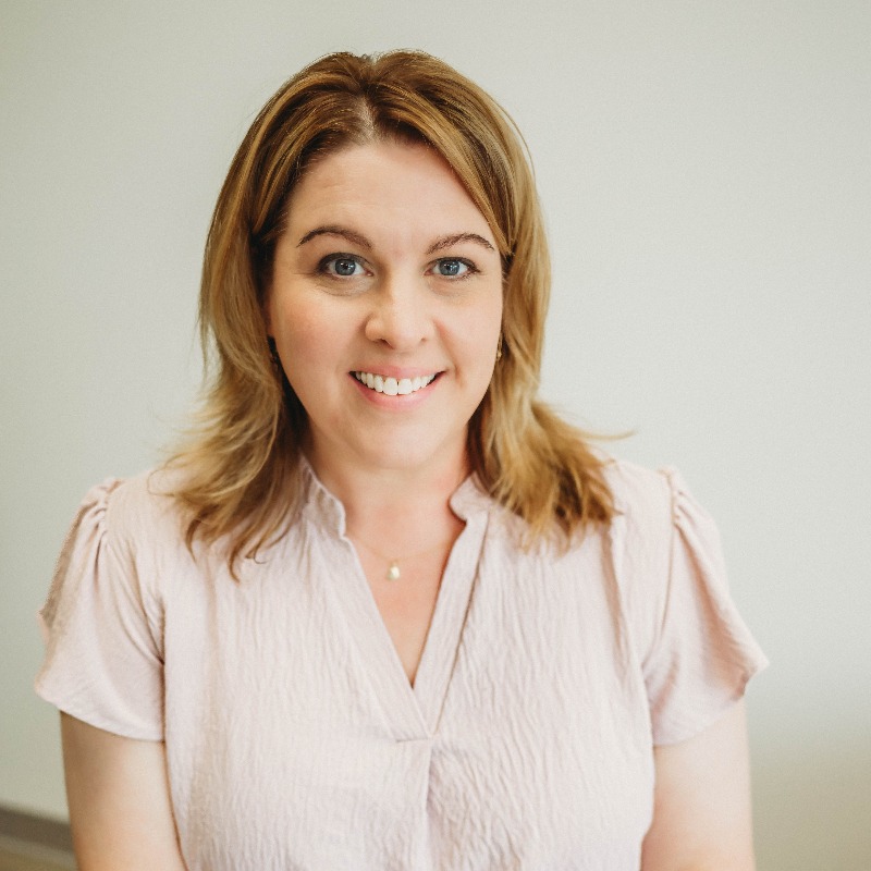 woman smiling at camera with chin resting on hand