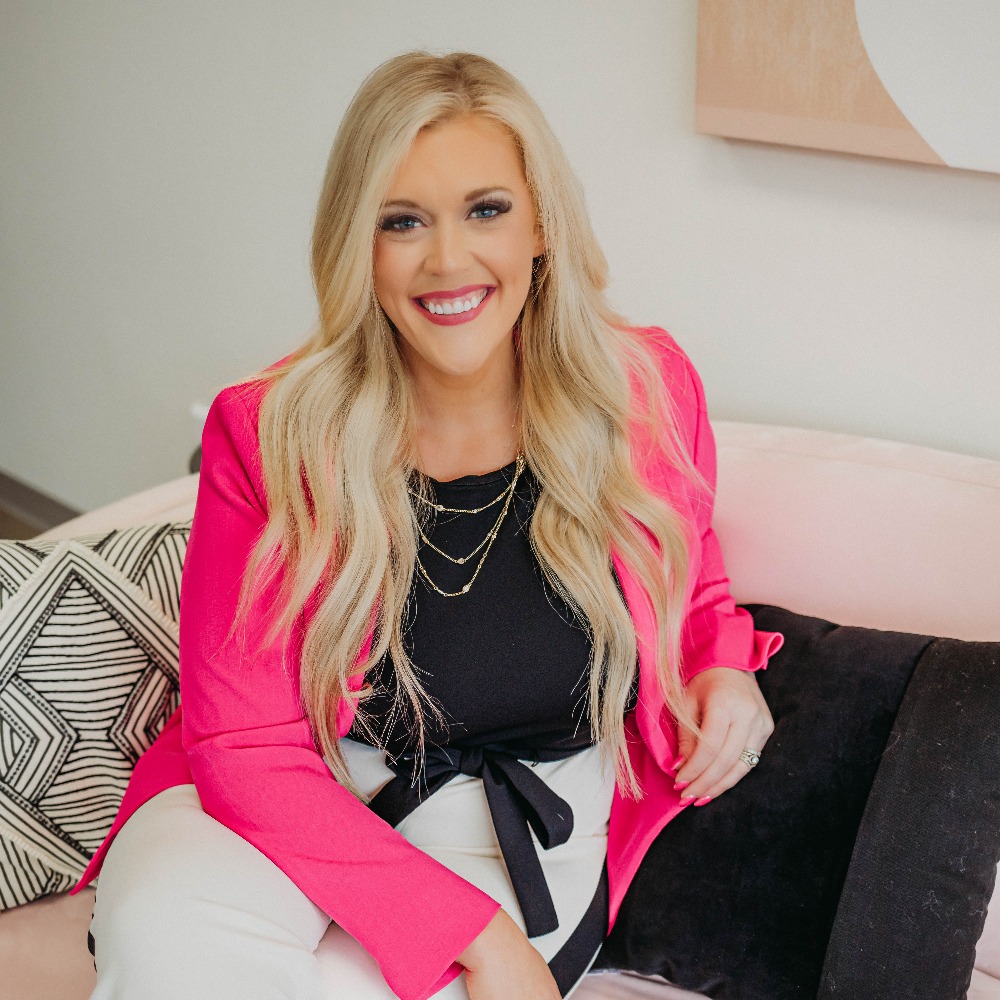 blonde woman sitting in a chair wearing a black blouse