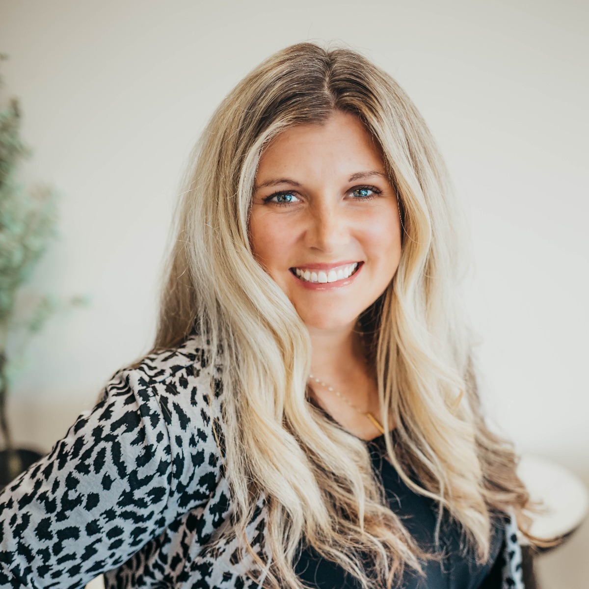 Woman with long blonde hair smiling at the camera in an office.