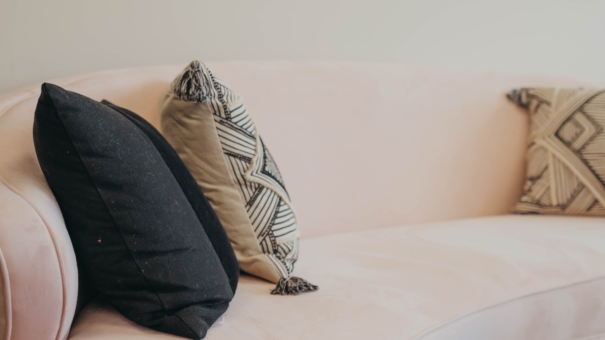 A light pink sofa with three pillows on it
