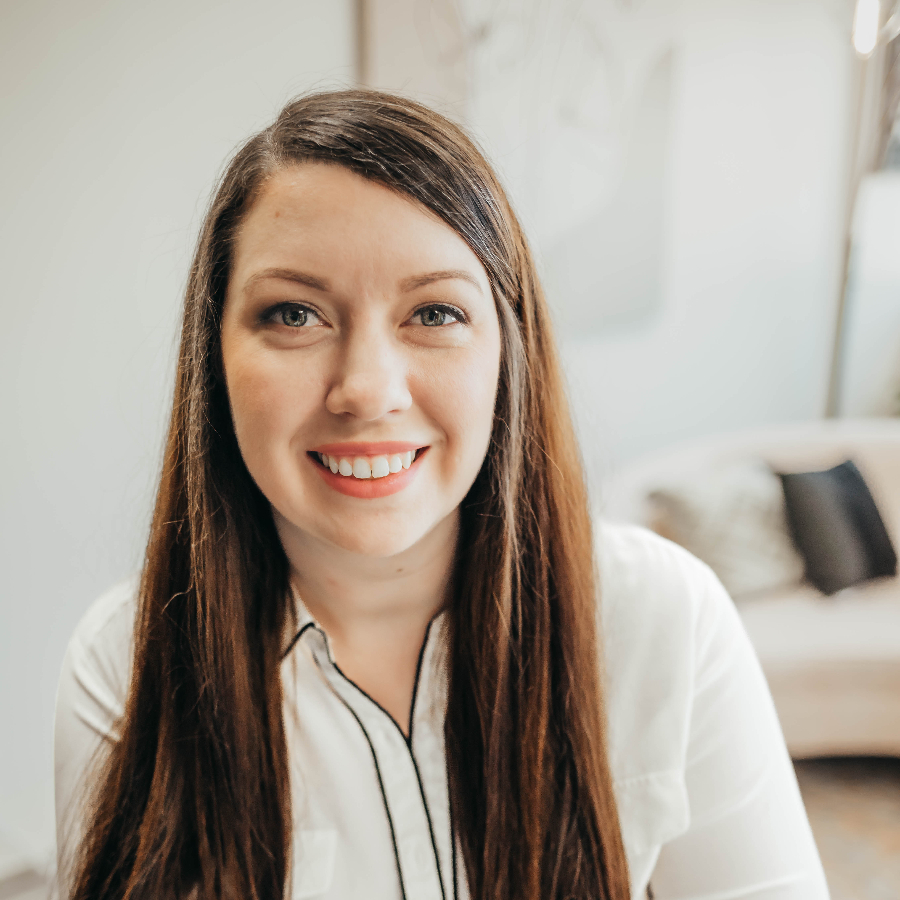 Brunette woman smiling in a white room.