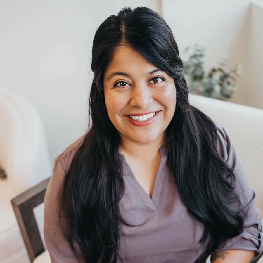 Woman smiling at the camera while sitting in a chair.