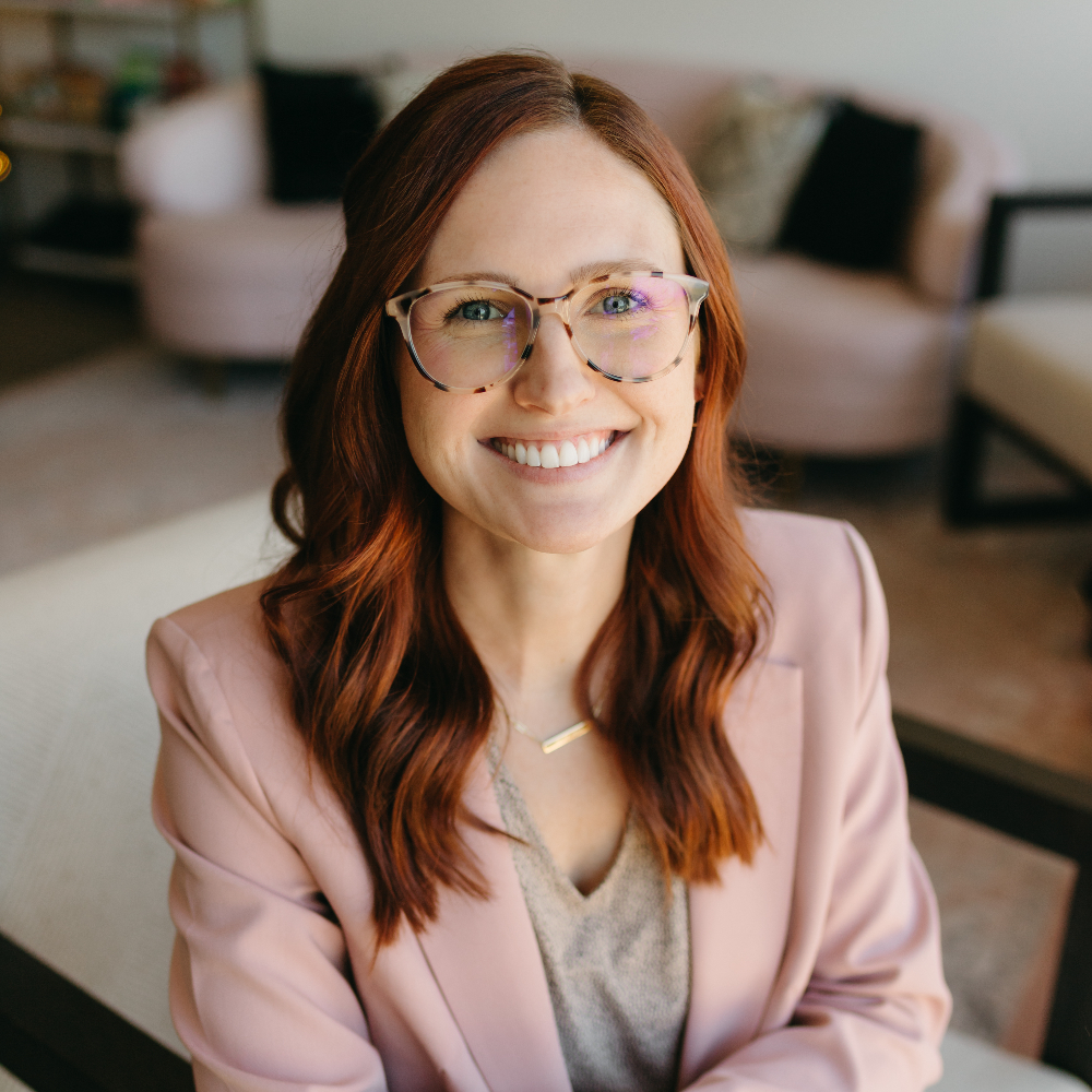 Woman with auburn hair smiling at the camera.
