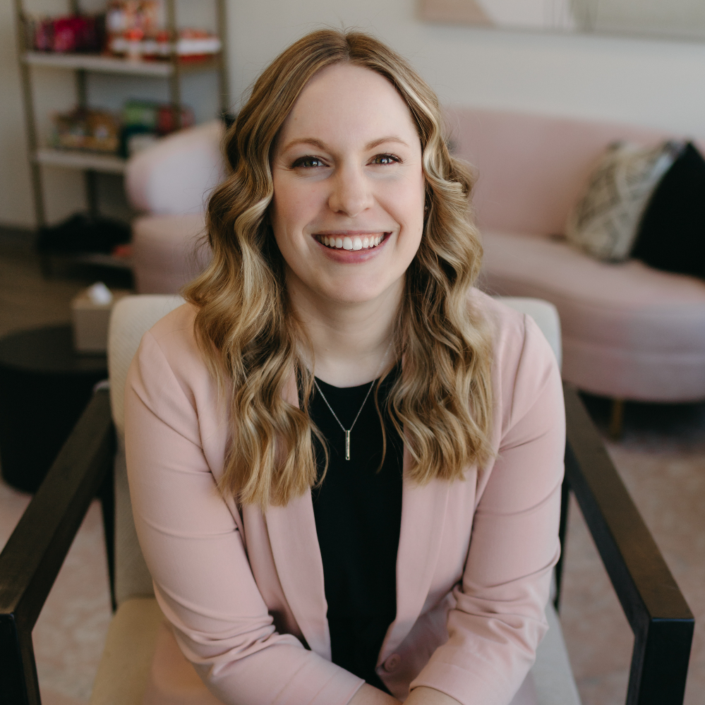 Woman in a light pink blazer smiling.