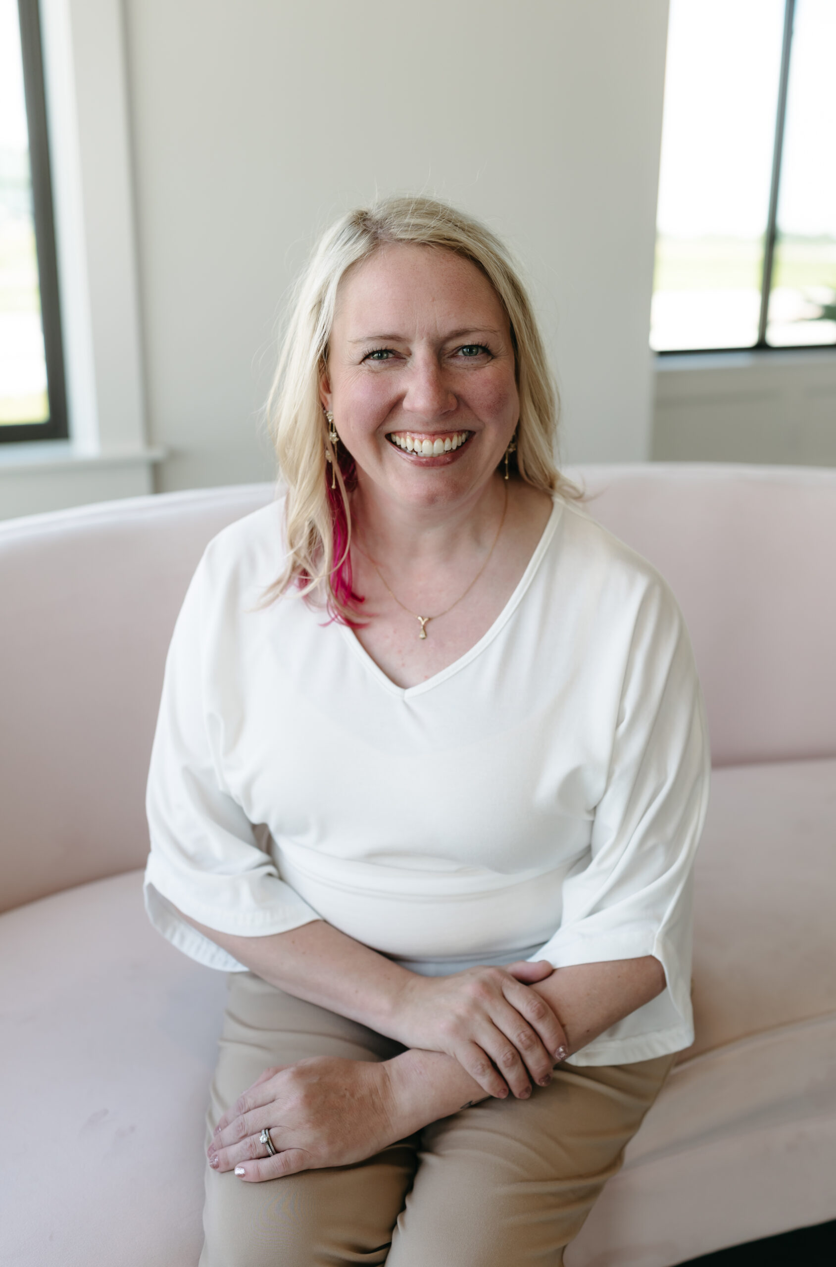 Blonde woman in a white top smiling.